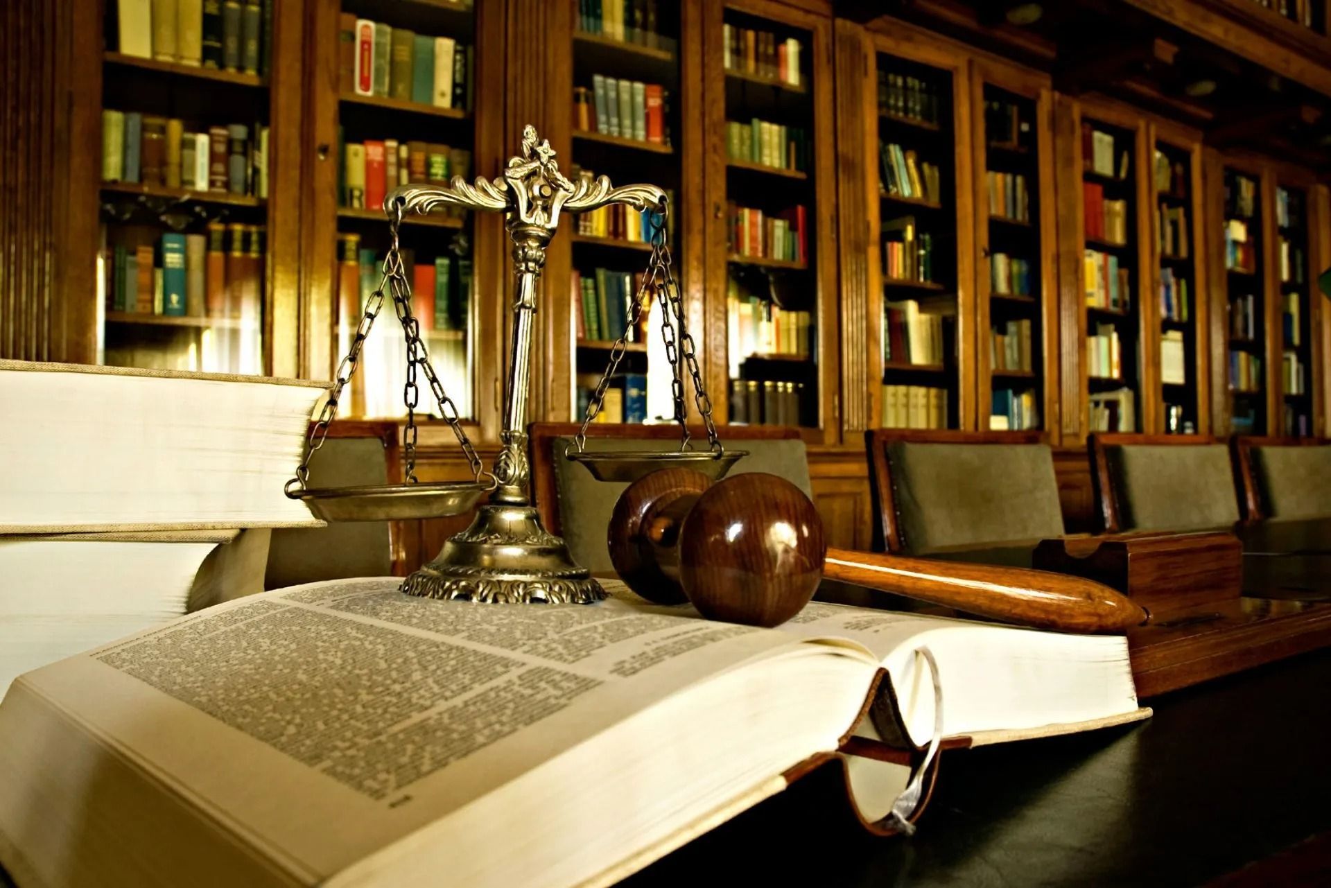 Scales of justice, gavel, and books on open book in a library setting.