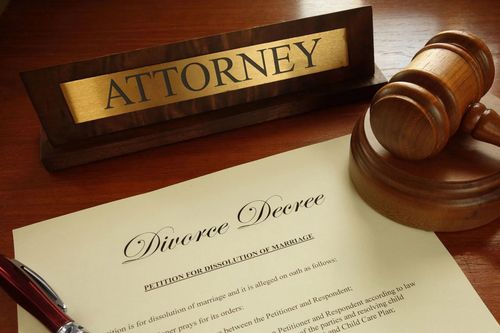Attorney desk sign, gavel, and divorce decree on a wooden surface.