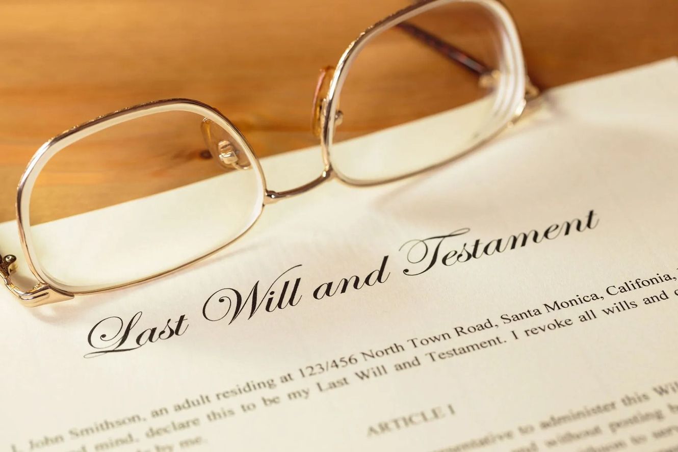 Last Will and Testament document with glasses on top, lying on a wooden surface.