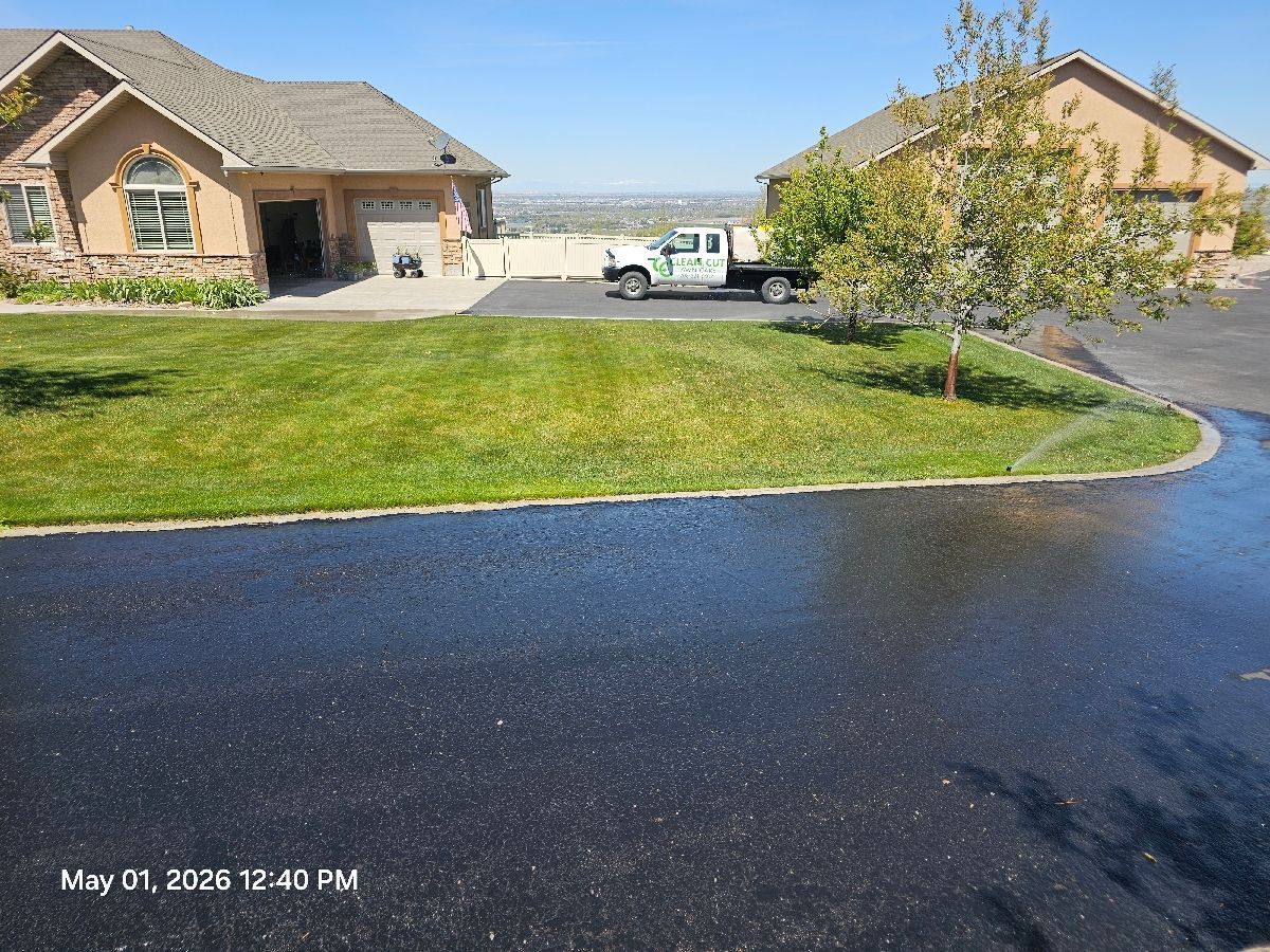 Suburban house with driveway, green lawn, and a white utility truck under a blue sky