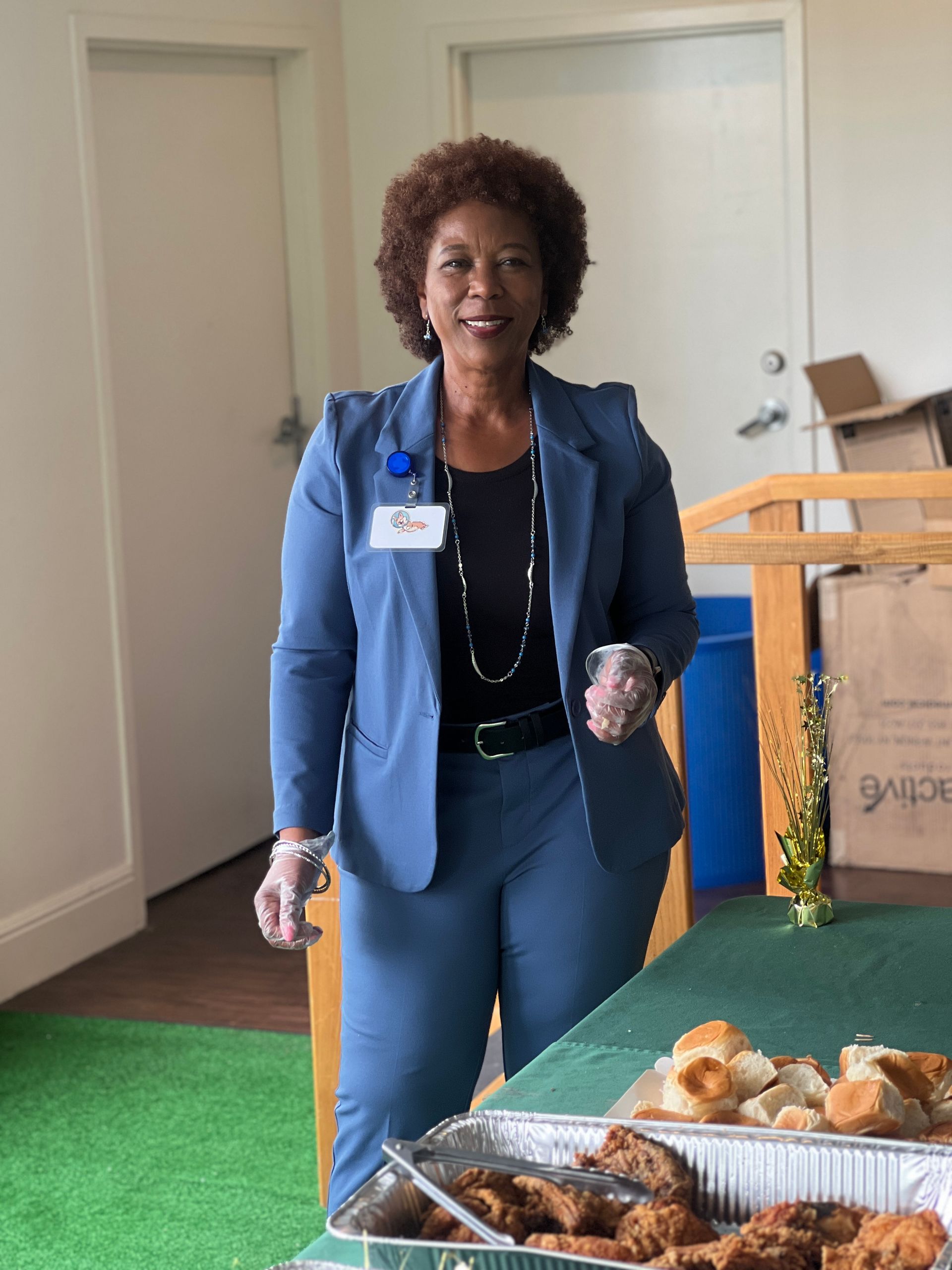 A woman in a blue suit is standing in front of a tray of food.