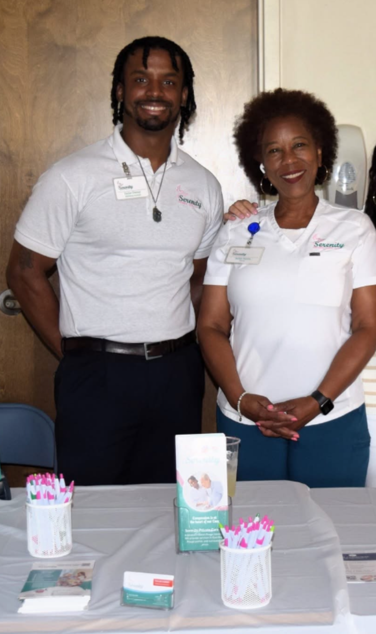 A man and a woman are posing for a picture in front of a table