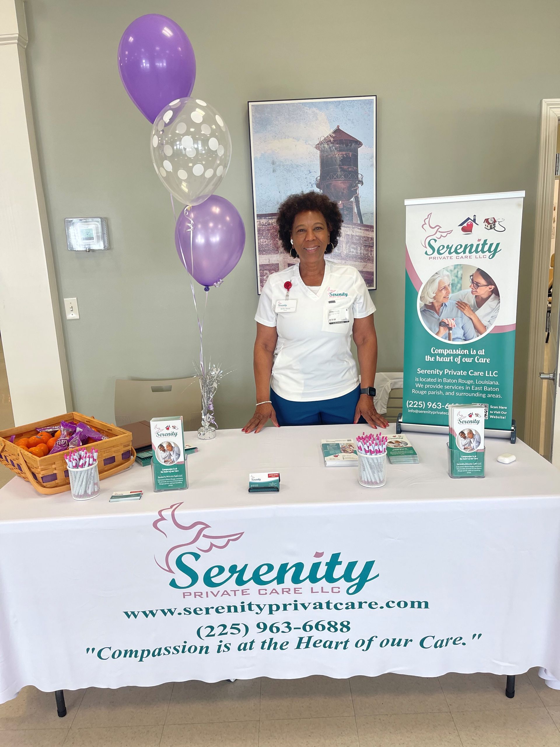 A woman is standing at a table with balloons and a sign that says serenity.