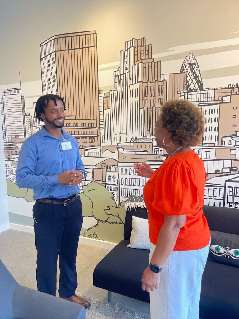 A man and a woman are talking in front of a mural of a city