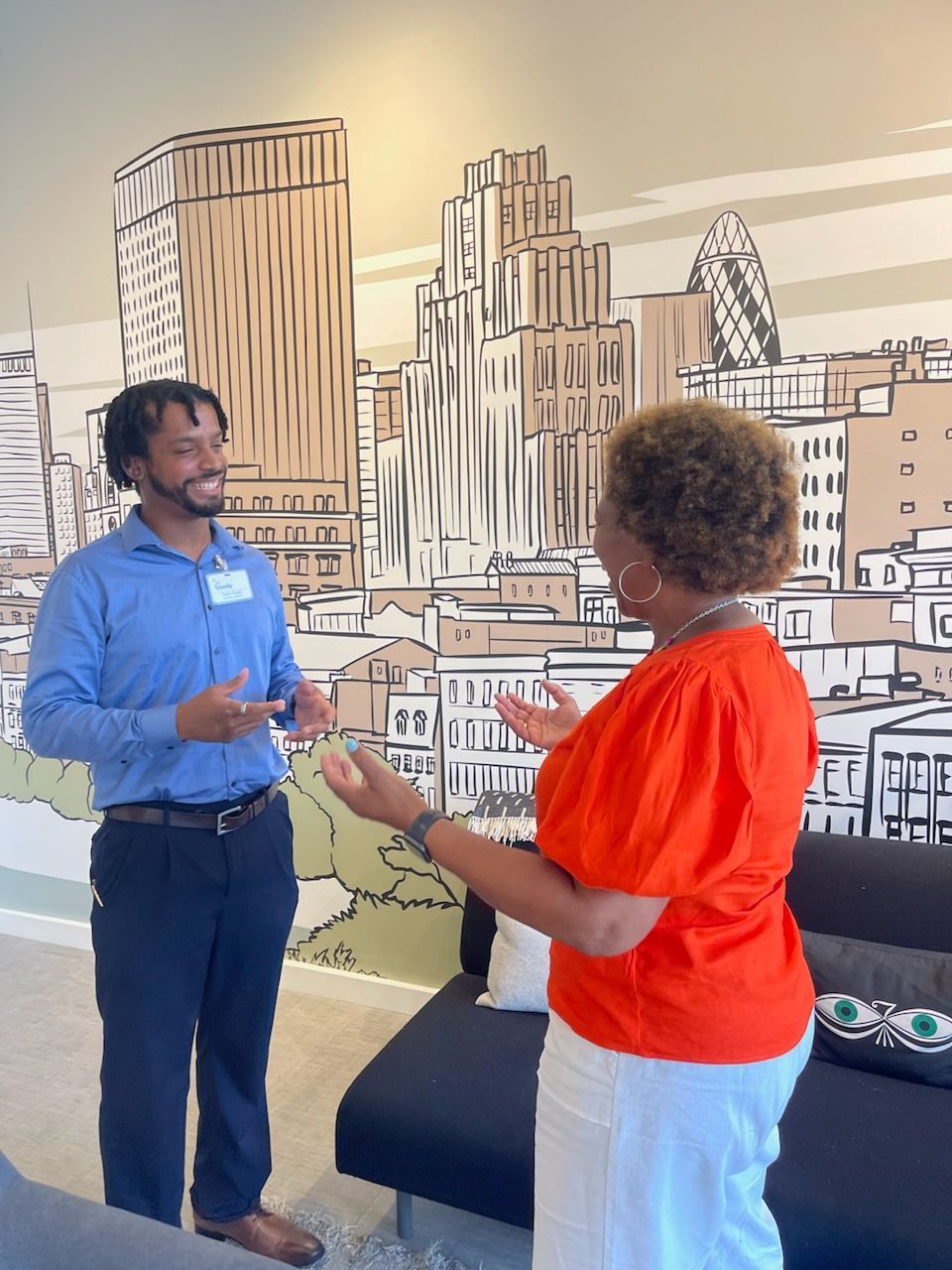 A man and a woman are talking in front of a city mural