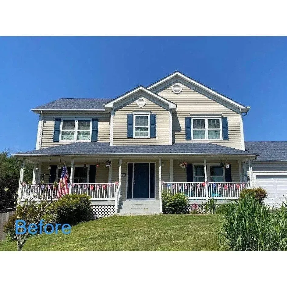 Before photo of a beige two-story house with white trim, porch, and green lawn under a blue sky