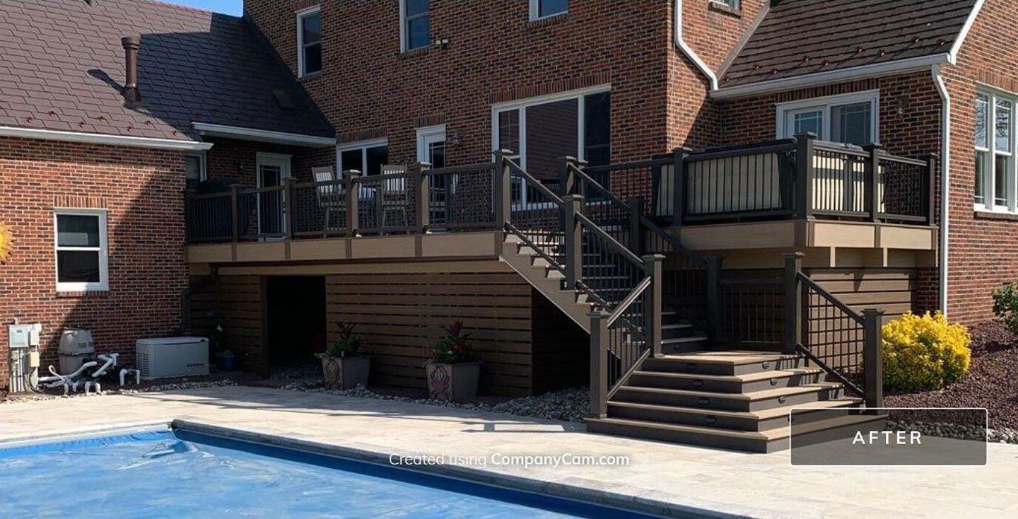 Backyard deck with stairs and a pool beside a brick house
