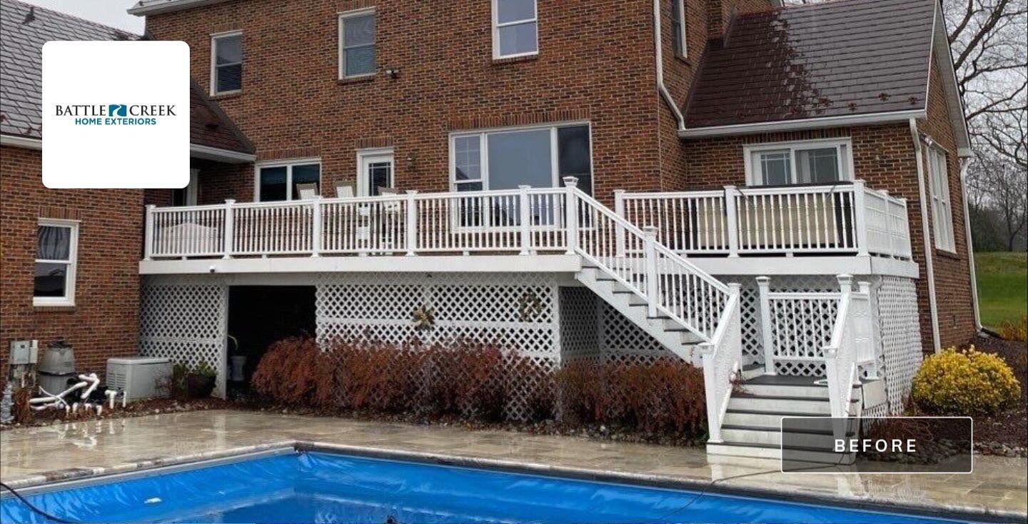 Brick house with white deck and stairs overlooking a backyard swimming pool