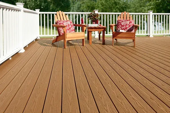 Deck with two wooden chairs, red patterned cushions, and a small table on a sunny porch overlooking greenery
