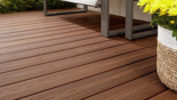 Wooden deck flooring beside a chair and a woven basket planter with yellow flowers