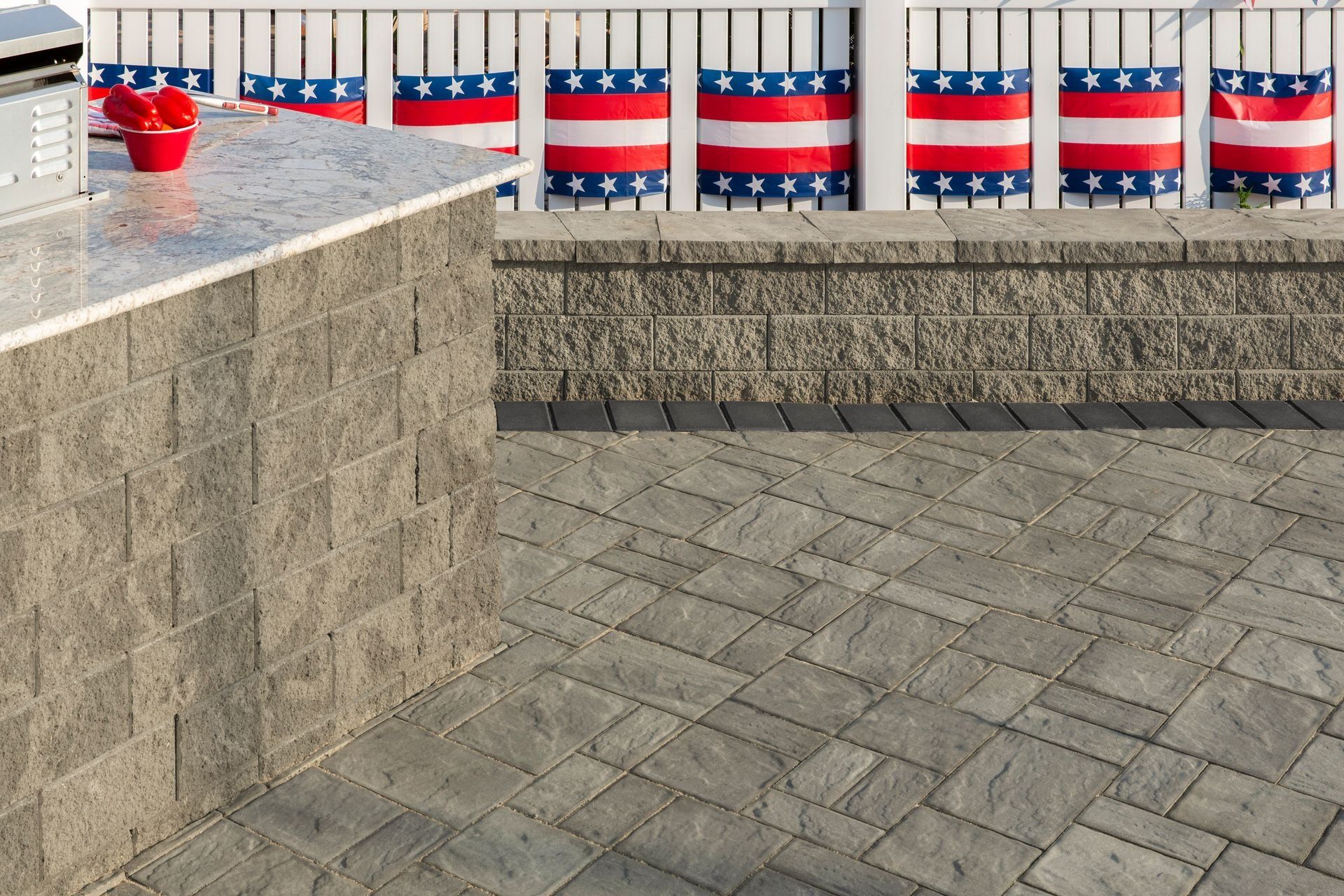 Stone courtyard with a low wall, decorative red-white-blue railings, and a red object on a ledge
