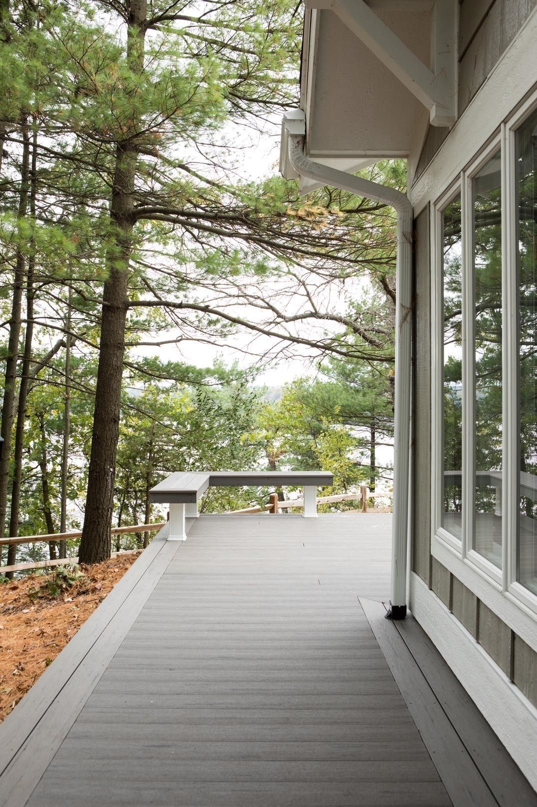 Covered deck beside trees overlooking a lake