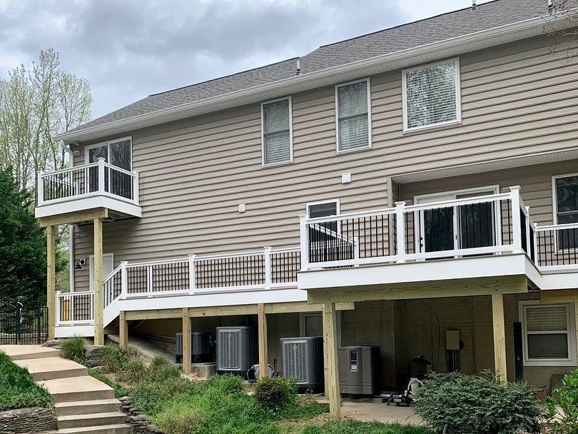 Townhouse exterior with raised back decks, beige siding, and exterior stairway along a landscaped slope