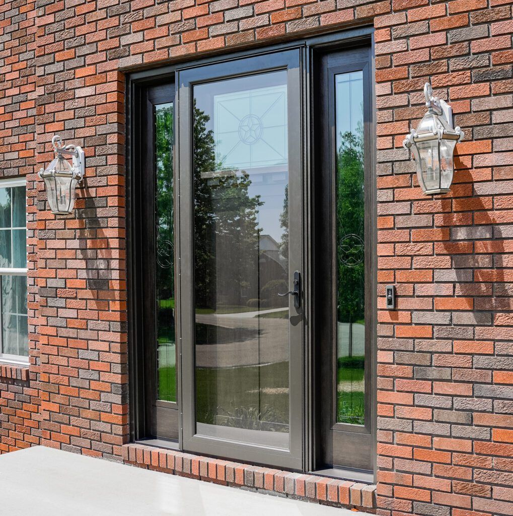 Brick building entrance with a glass front door and two wall-mounted lanterns