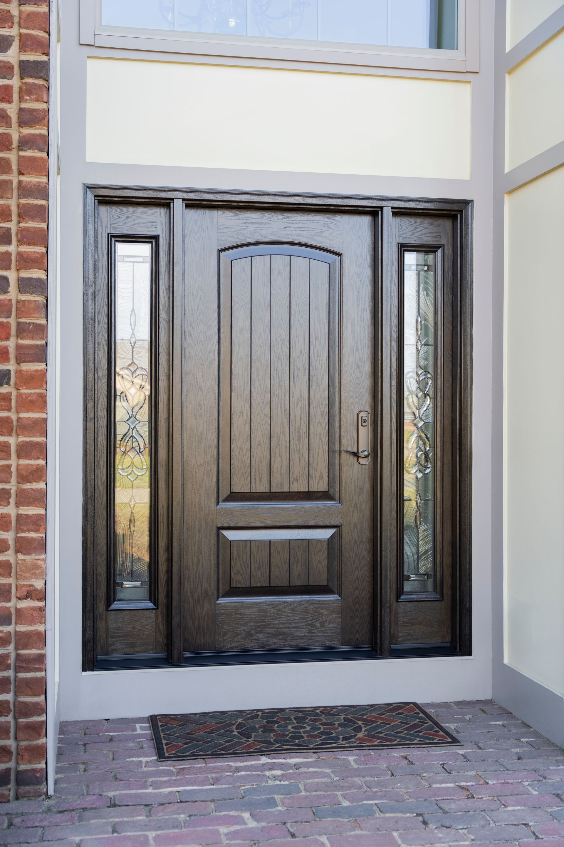 Dark wood front door with glass sidelights and brick entryway