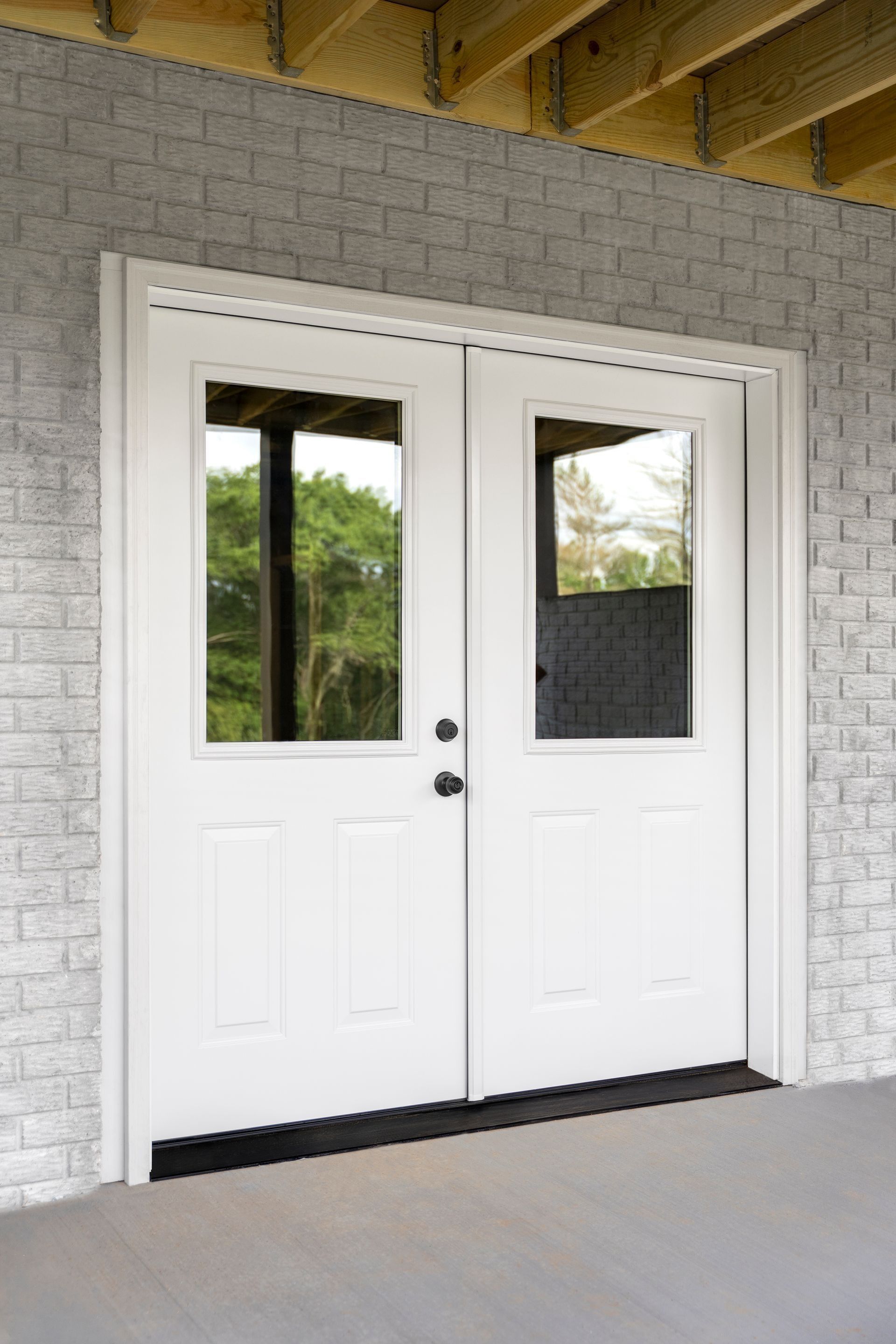 White double front doors with small glass windows on a covered porch.