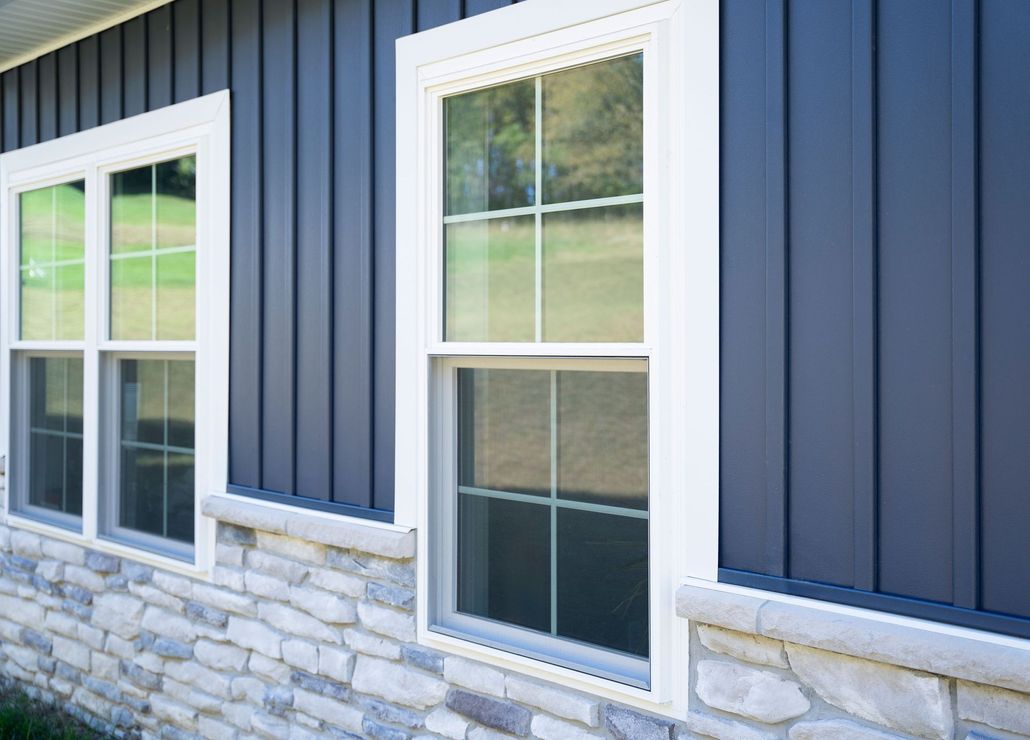 Blue house exterior with white-trimmed windows and stone veneer base
