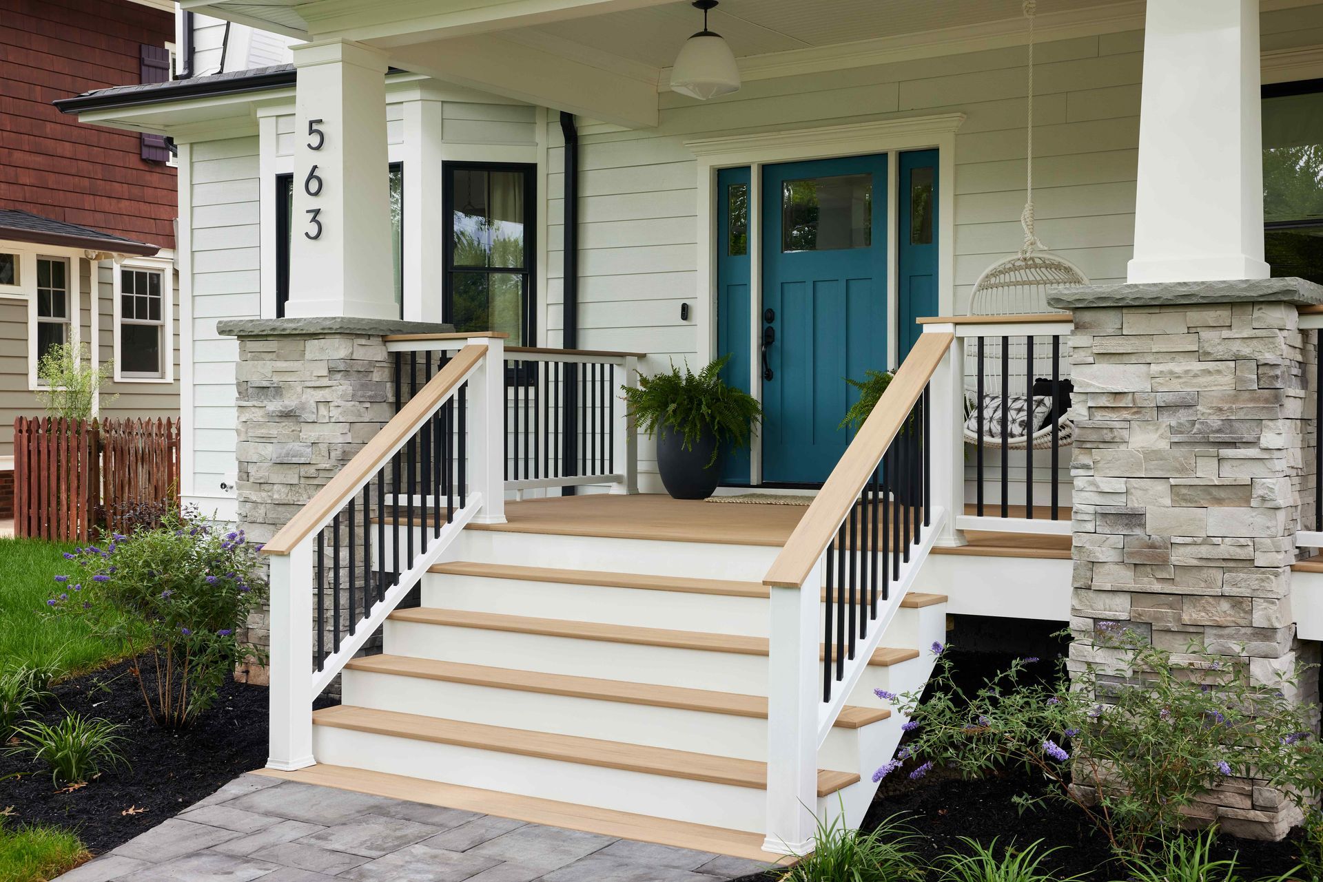 Front porch with stone columns, white steps, and a blue front door of a house.
