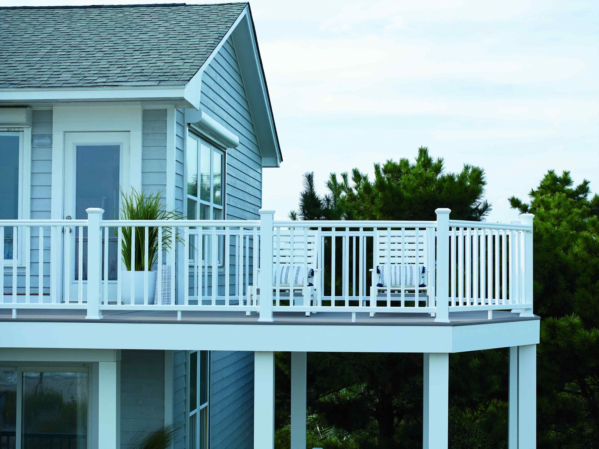 White house deck with railing overlooking water and trees