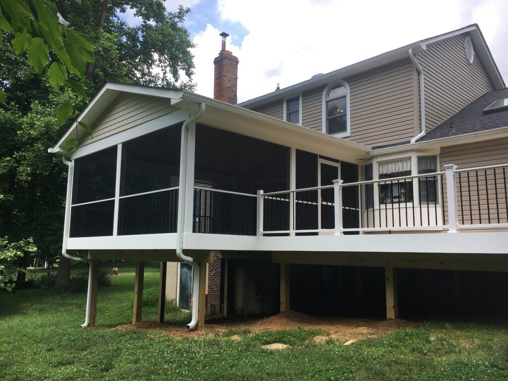 Raised screened porch attached to a house, with white railings and lattice skirting above the ground