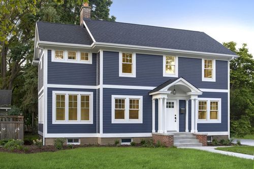Blue two-story house with white trim, front porch, and neatly kept lawn