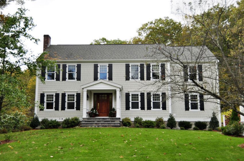 White two-story house with black shutters, a red front door, and a green lawn