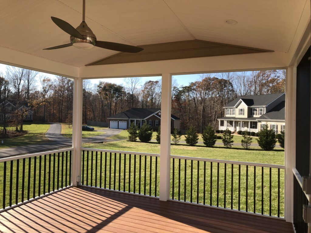 Covered porch overlooking a grassy yard and neighboring houses on a sunny day