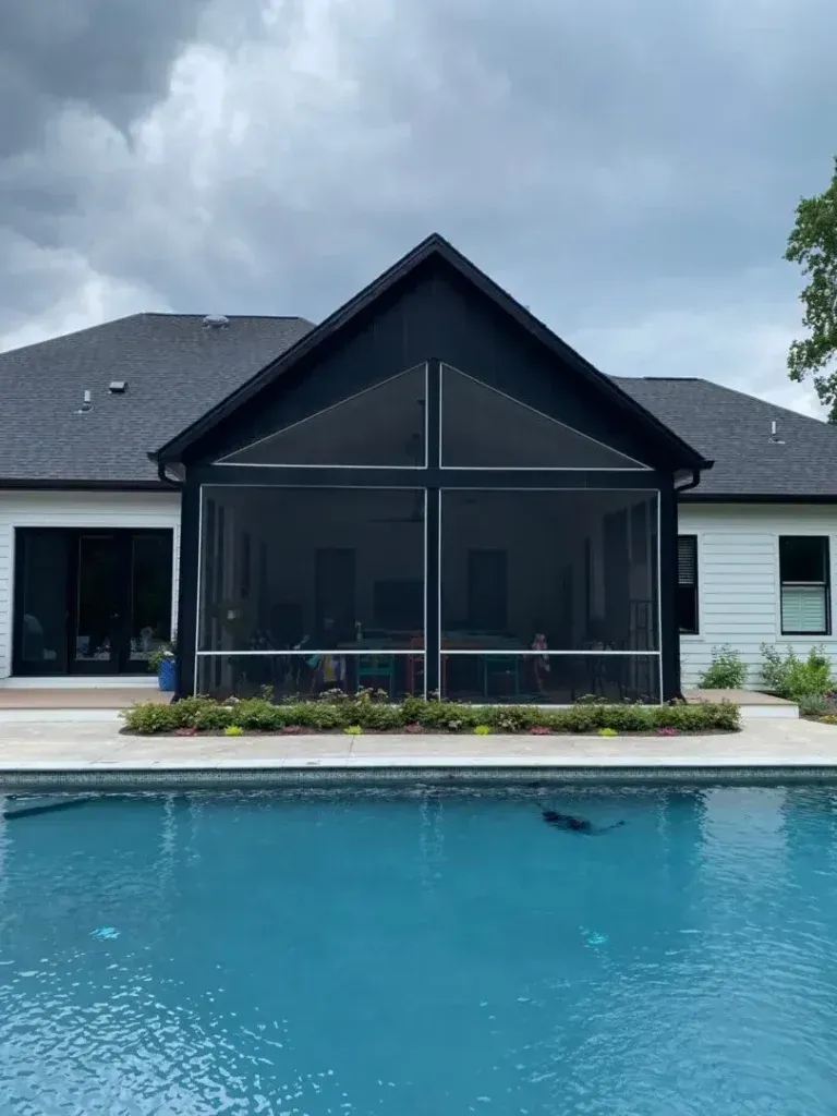Backyard pool with modern house and screened patio under cloudy skies