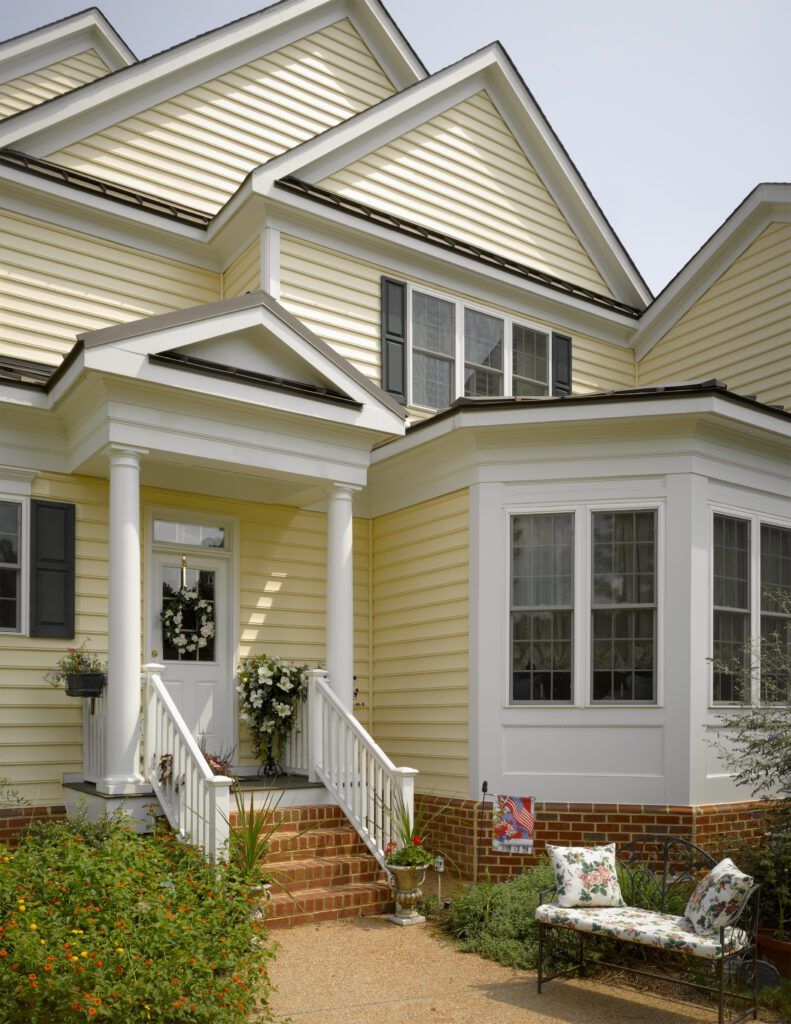 Yellow house with white trim, front porch, bay window, and garden path