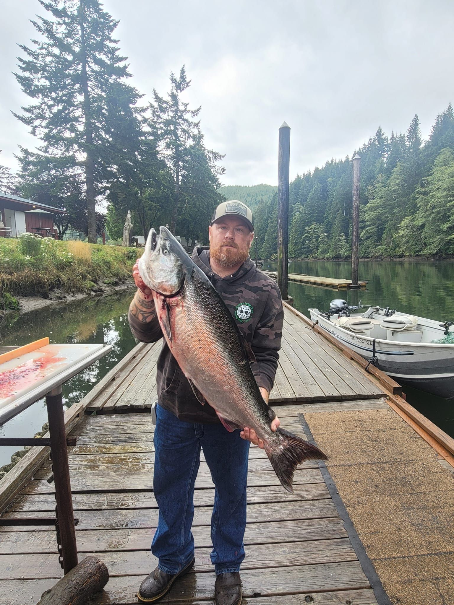 A man is standing on a dock holding a large fish.