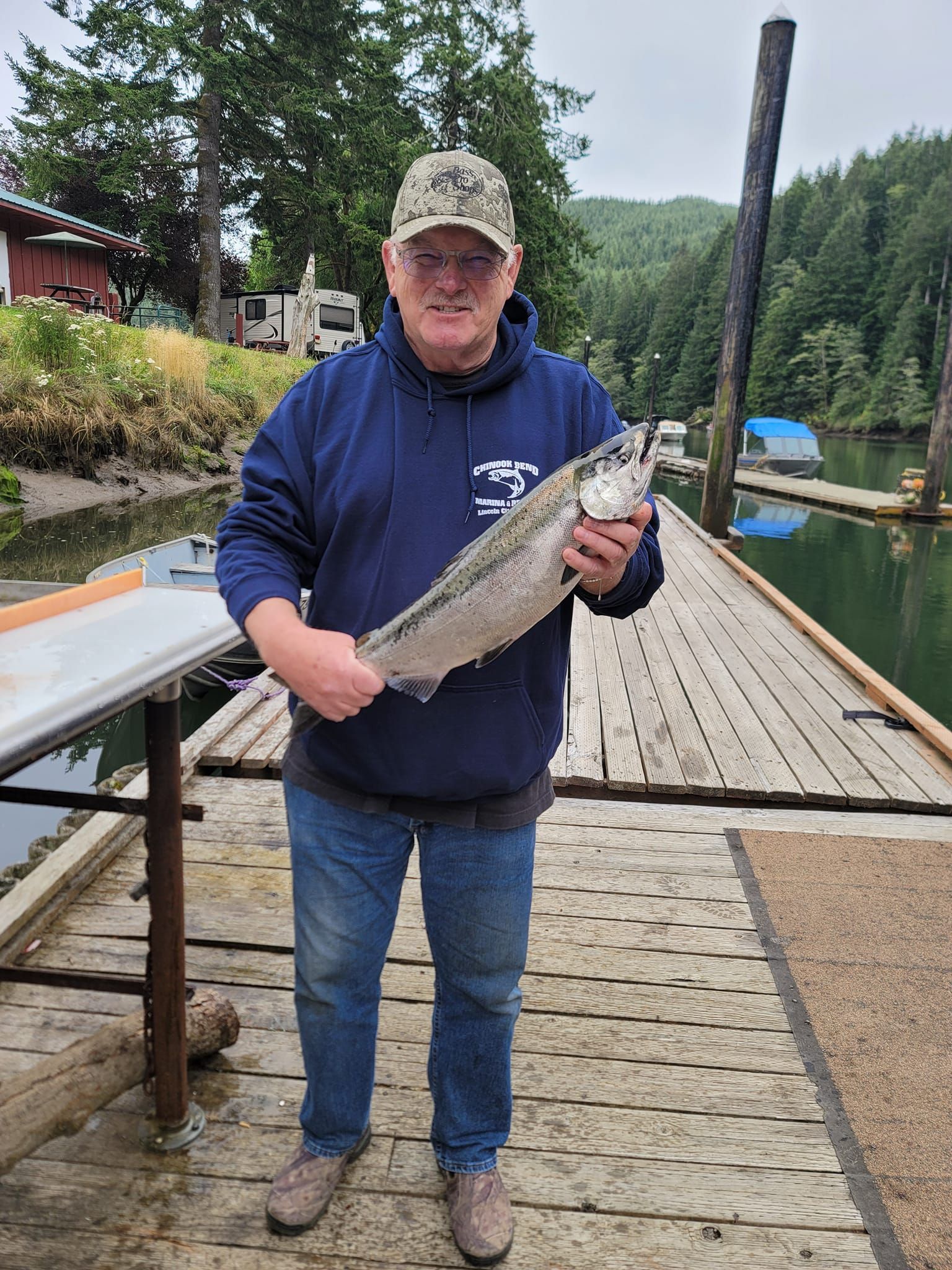 A man is standing on a dock holding a large fish.