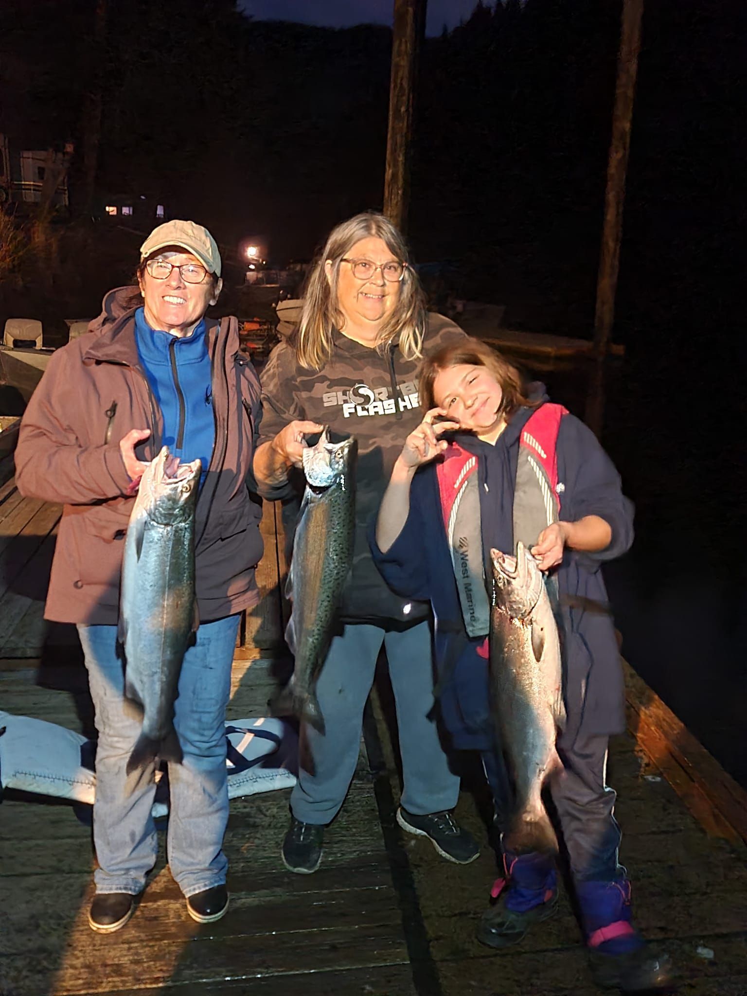 A group of people standing next to each other holding fish.