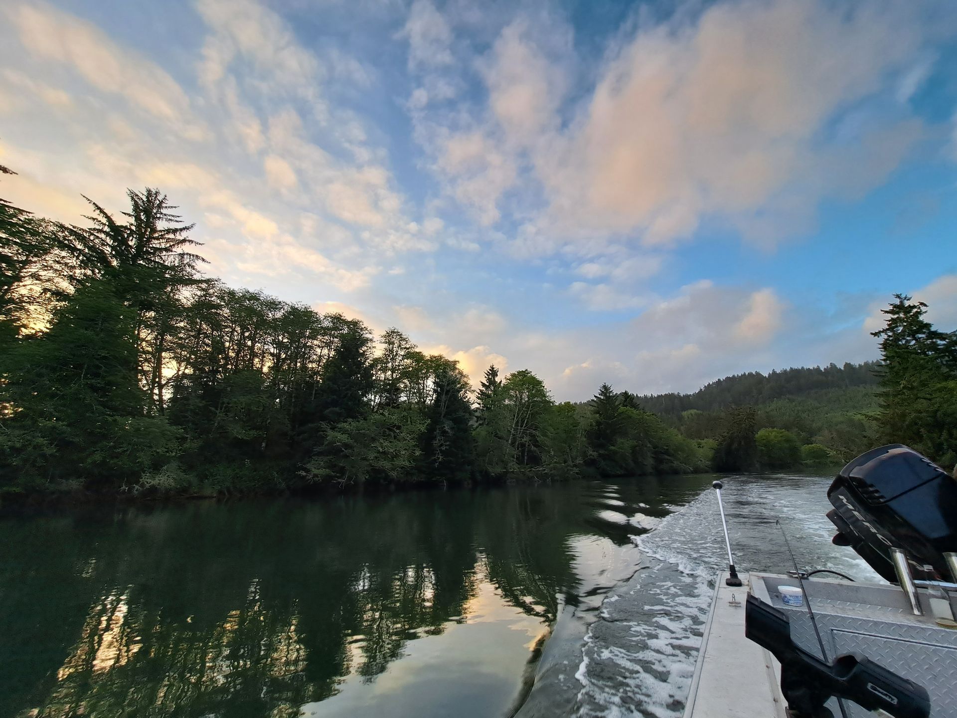 A boat is going down a river with trees in the background.