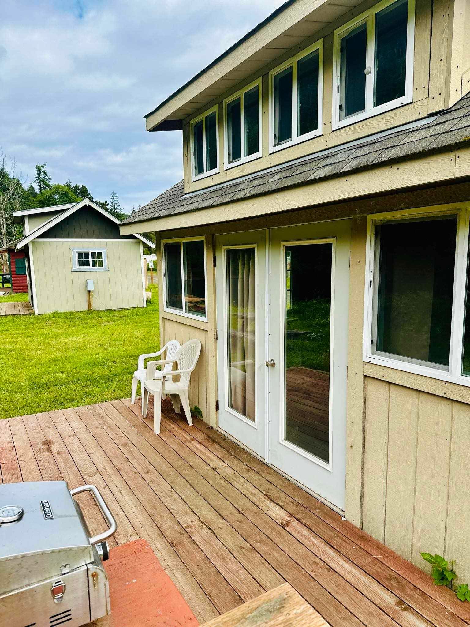 A house with a wooden deck and a grill in front of it.