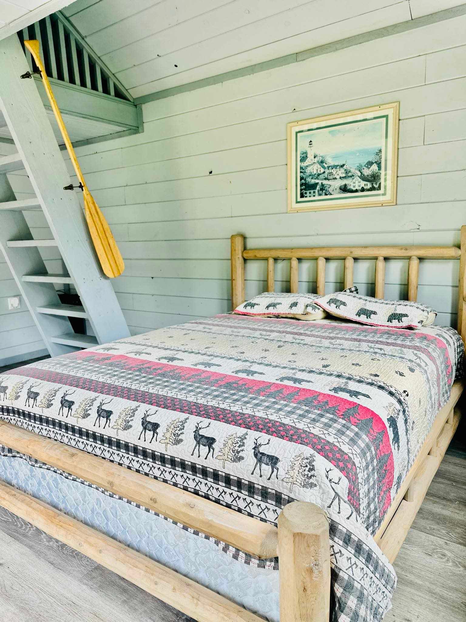 A bedroom with a bed , stairs and a picture on the wall.