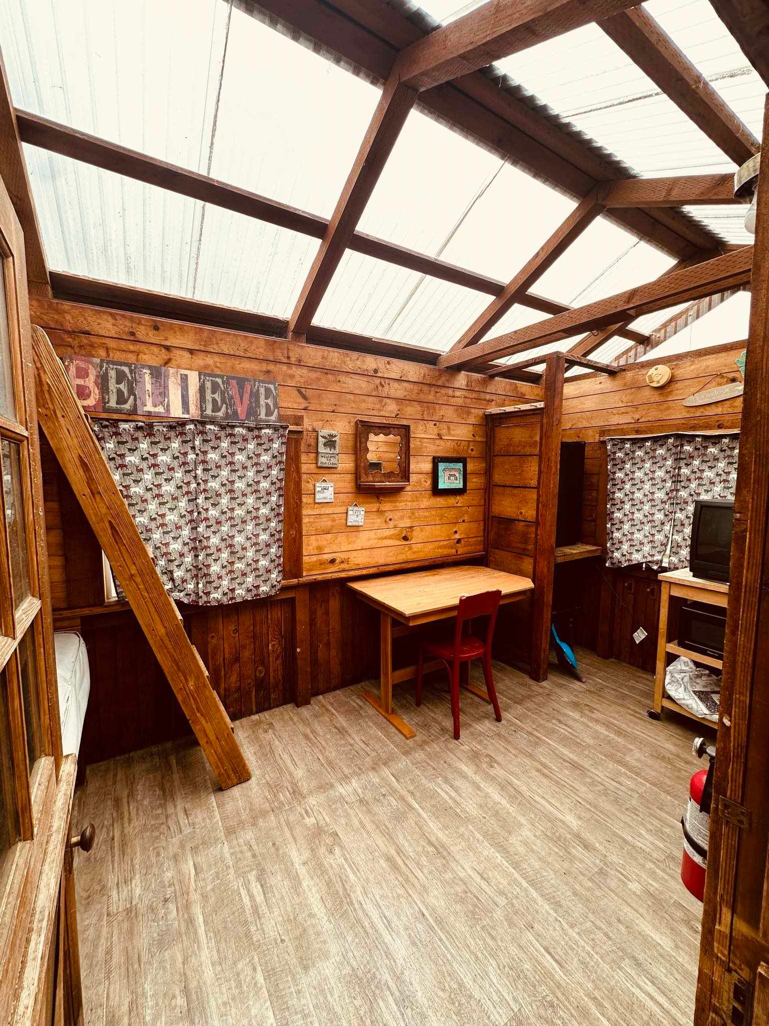 A wooden room with a table and chairs in it.