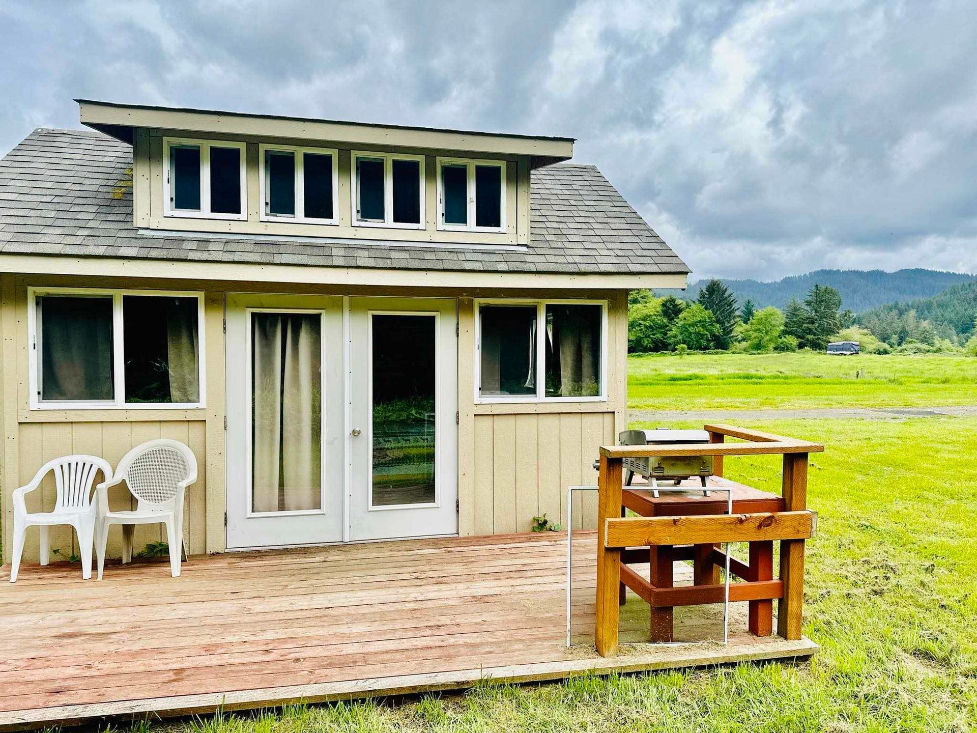 A small house with a table and chairs on the porch.