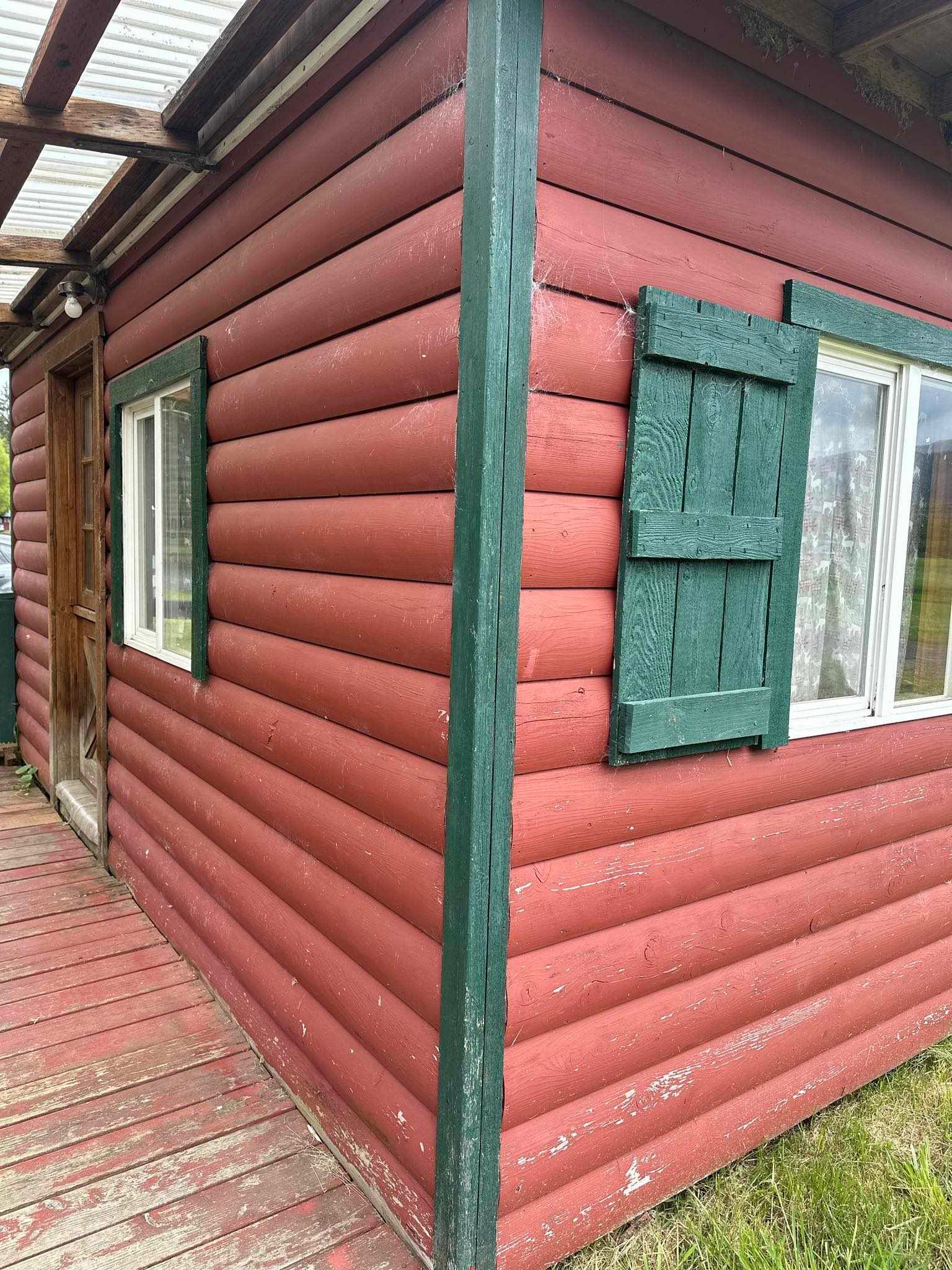 A red log cabin with green shutters on the windows.