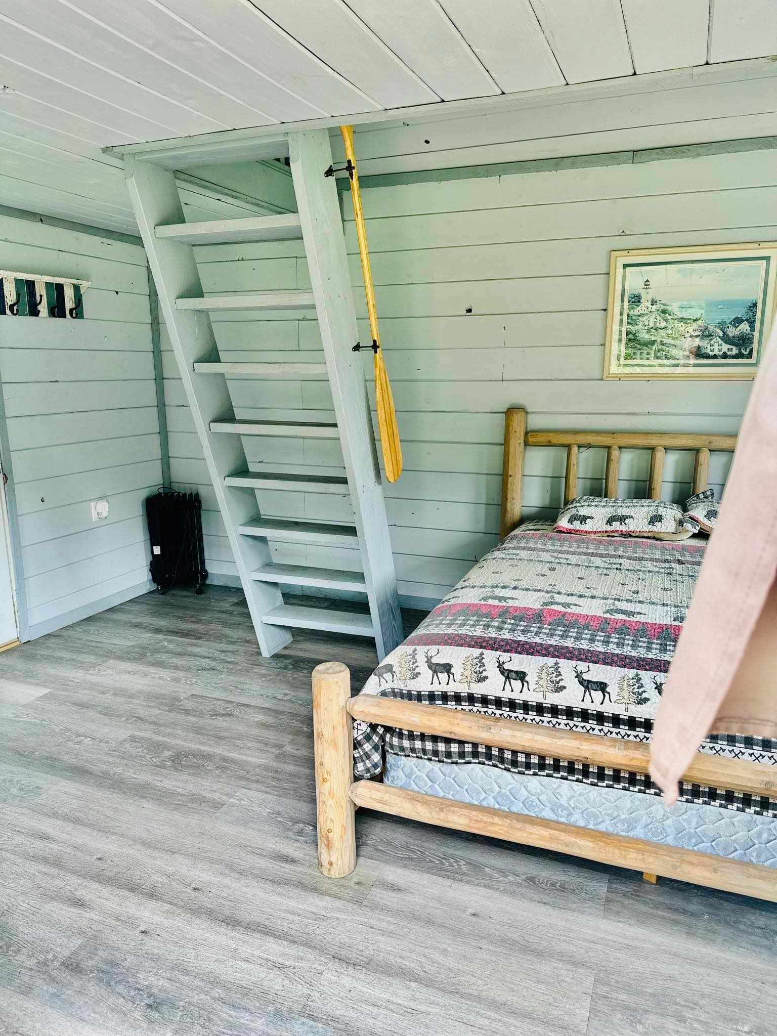 A bedroom with a bed , stairs and a picture on the wall.