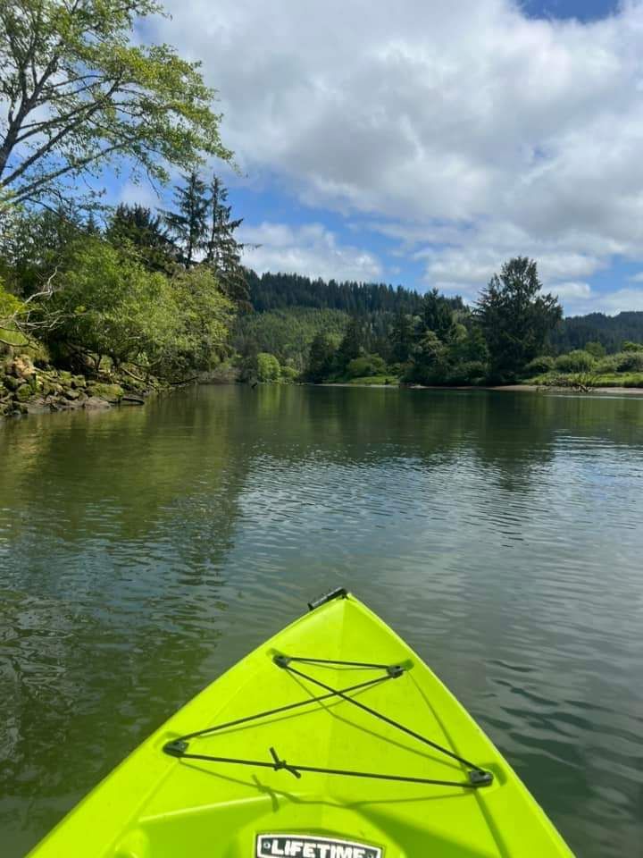 A yellow kayak is floating on a river with trees in the background.
