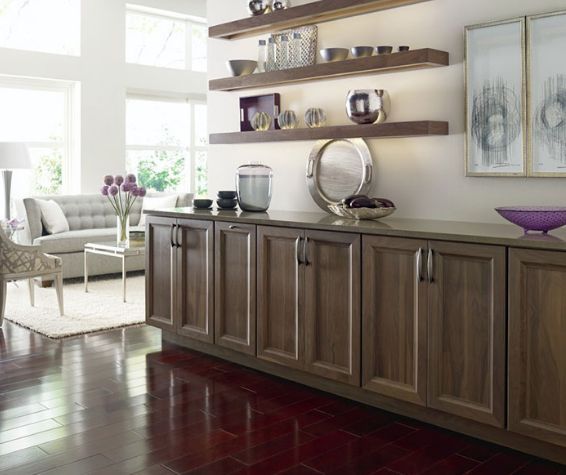 A wooden sideboard with shelves above, featuring decorative bowls and art, set in a modern, light-filled living room.