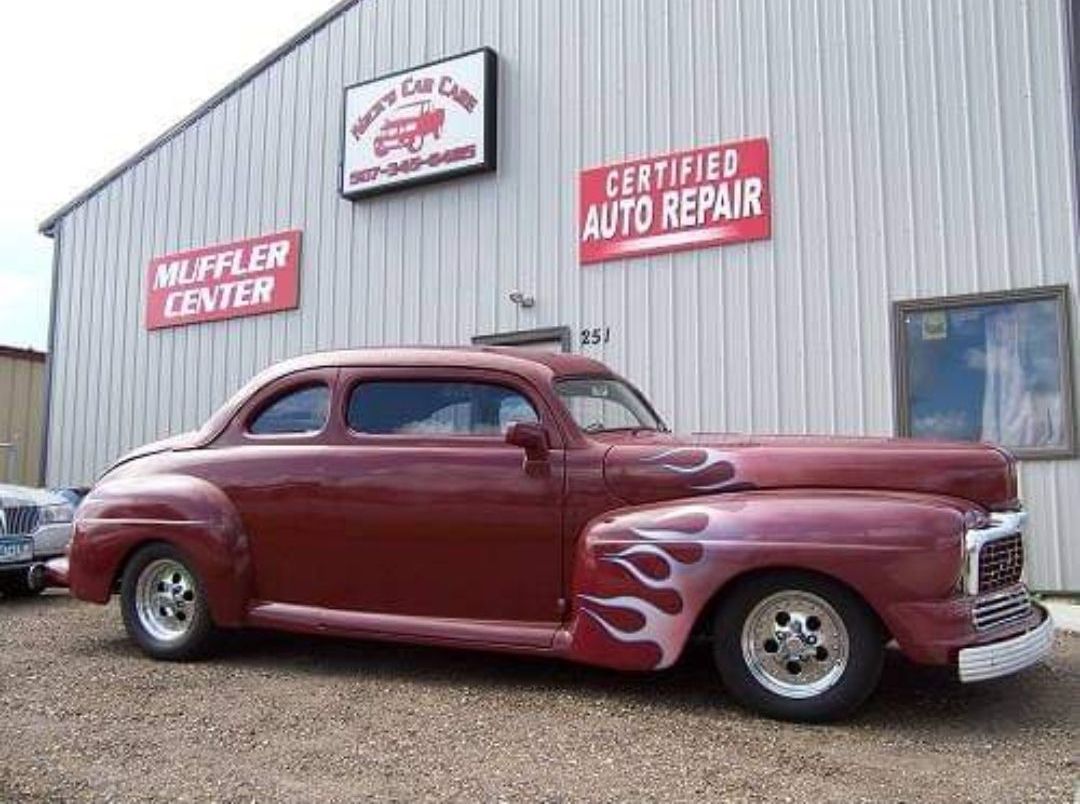 a red car is parked in front of a building that says certified auto repair