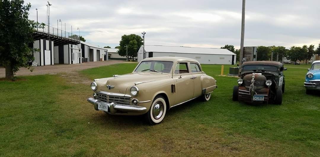 three old cars are parked in a grassy field