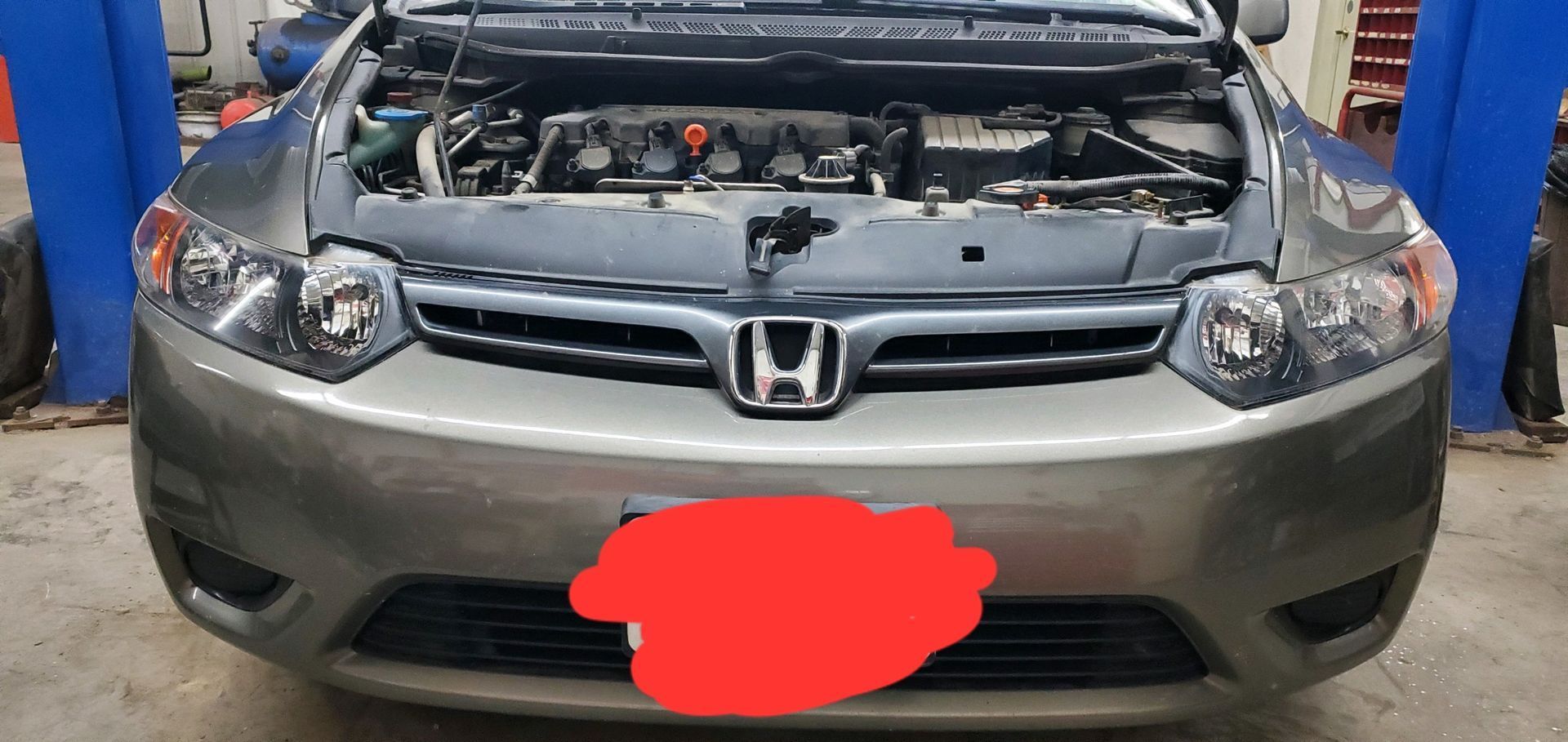 a gray honda civic with the hood up in a garage