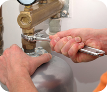 A pair of hands using a wrench to tighten a pipe
