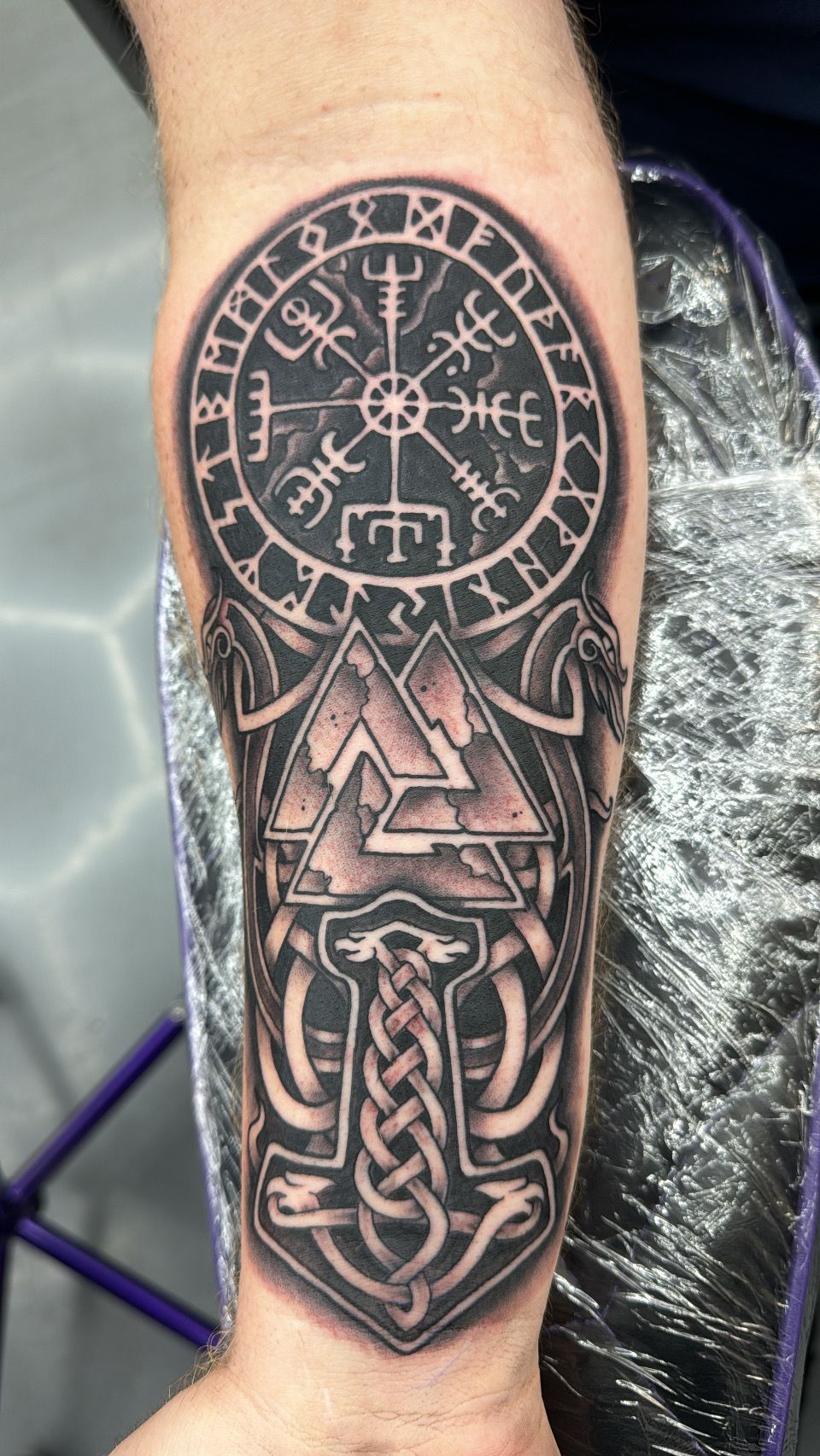 A man has a tattoo of a compass and an anchor on his forearm