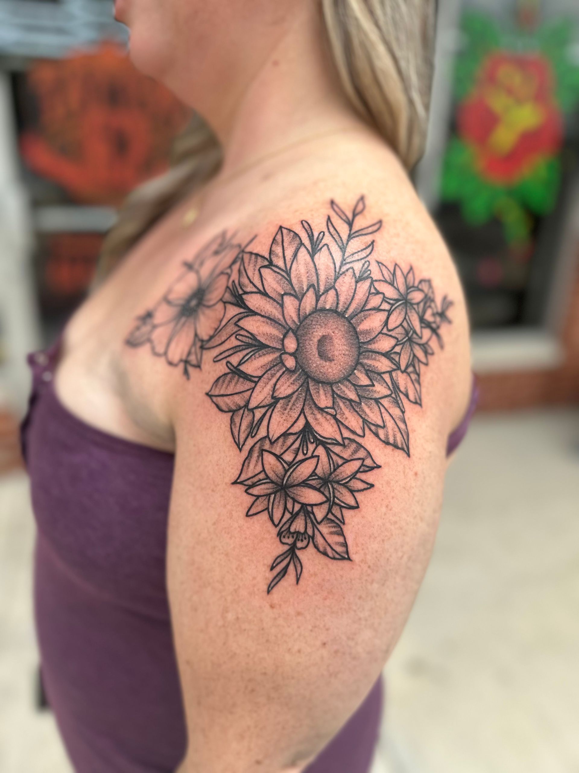 A woman has a tattoo of flowers on her shoulder