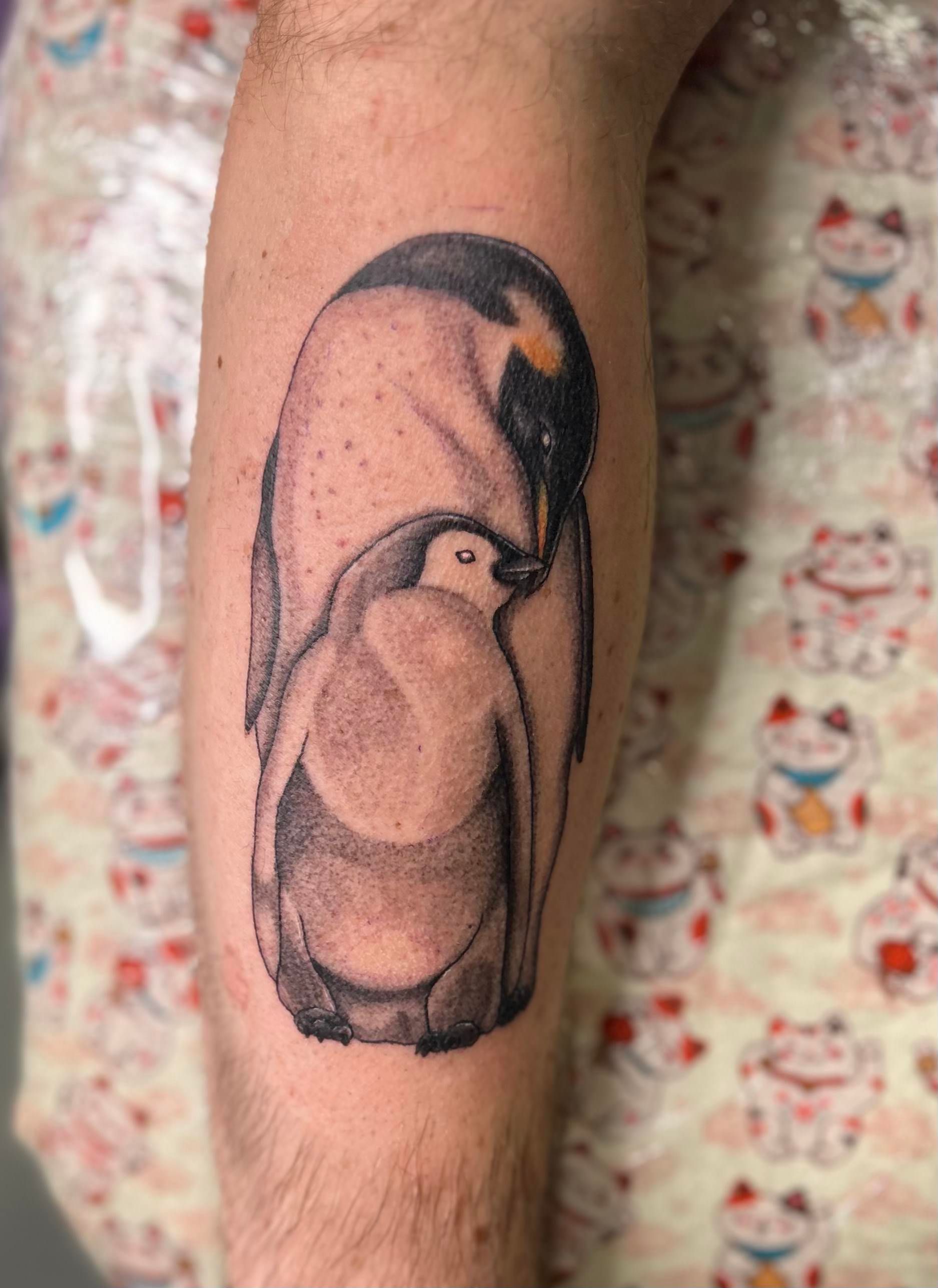 A tattoo of two penguins on a person 's leg