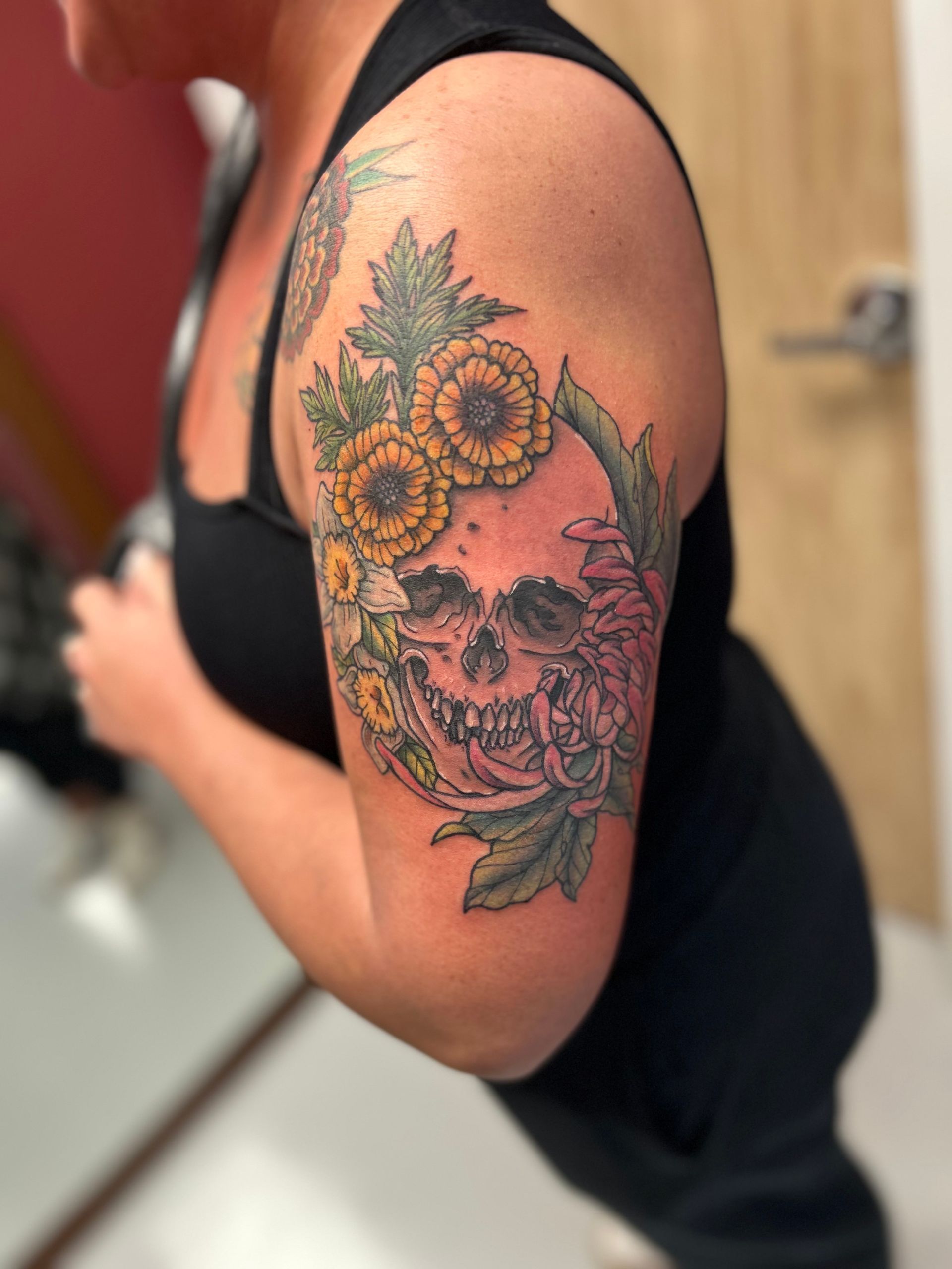 A woman has a tattoo of a skull and flowers on her arm
