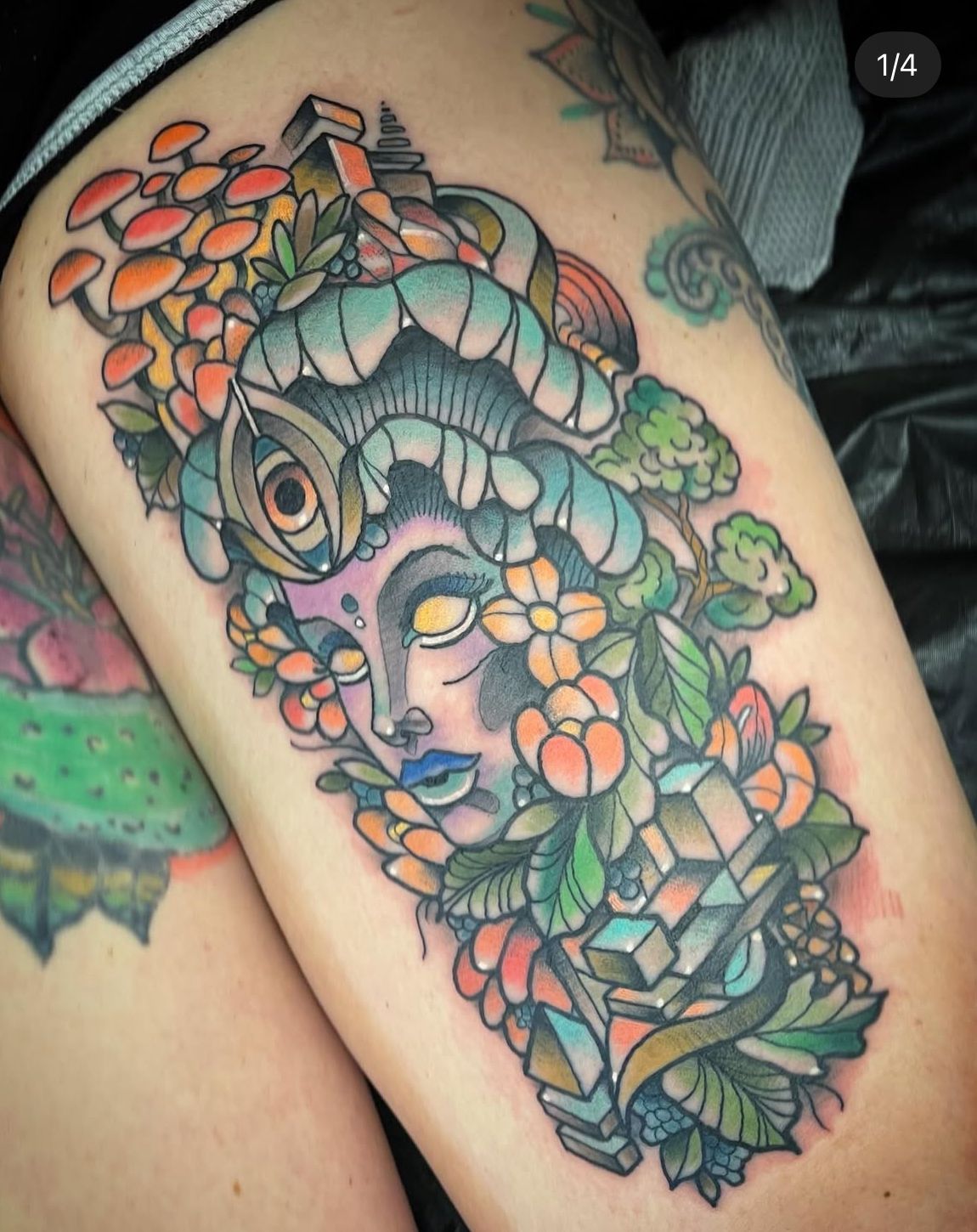 A woman has a tattoo of a woman surrounded by flowers and mushrooms